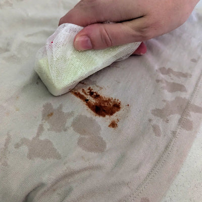 Wetting the stain remover bar and applying to a tomato sauce stain